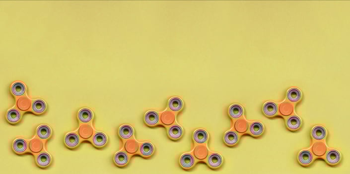 Many orange fidget spinners lies on texture background of fashion pastel orange color paper photo