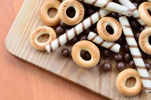 Crispy tubules, chocolate melting balls and bagels lie on a wooden surface. Mix of various sweets photo