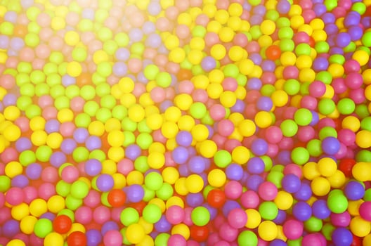Many colorful plastic balls in a kids' ballpit at a playground. Close up pattern photo