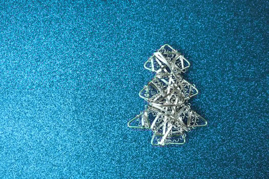 Festive New Year Christmas happy blue shiny joyful background with a small toy metal iron silver homemade Christmas tree. Flat lay. Top view. Holiday decorations photo