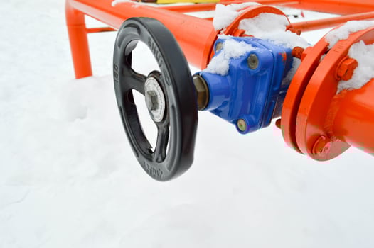 Industrial shut-off regulating protective pipe fittings. Black valve for opening, closing on an iron orange metal pipe with flanges, studs, nuts against the background of white snow in winter photo