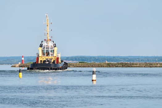 Tugboat, tow ship inner harbor sea city. Vessel for tow another ships. Buoys on the water, copy space photo