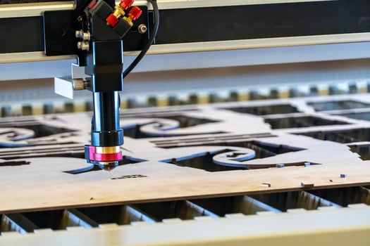 laser cutting machine, cutting wood sheets, while a man takes care of the process, latin america photo