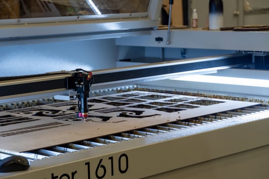 laser cutting machine, cutting wood sheets, while a man records the process, mexico photo