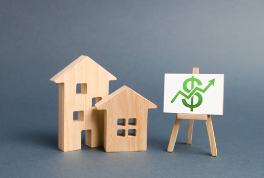 Wooden figures of houses and a poster with green arrow up. The concept of real estate value growth. Increase liquidity and attractiveness of assets. Raising the rent or cost of buying a home. photo