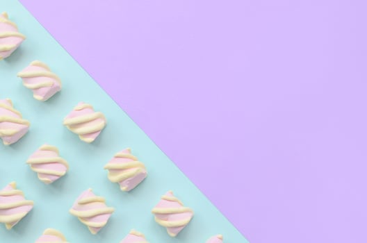 Colorful marshmallow laid out on violet and blue paper background. pastel creative textured pattern. minimal photo