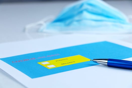 pen on Covid-19 test result paperwork photo