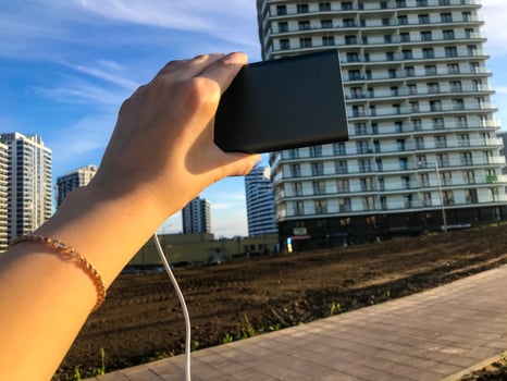 girl holding a charging block on the background of a multi-storey residential building. she is wearing a gold fashion bracelet. the building is made in the Arabian style, brown base of the entrances photo