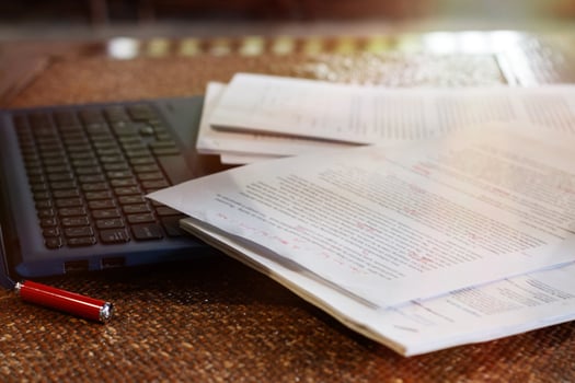 blurred paperwork over laptop on table in office photo