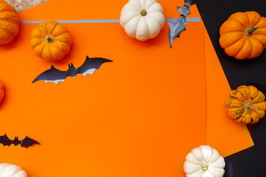 Halloween flat lay composition of black paper bats fand pumpkins on orange background. Halloween concept. photo