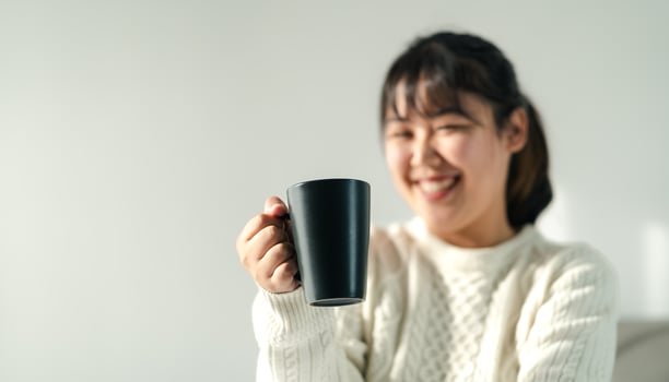 Smiling young woman holding a coffee cup in the bedroom. photo