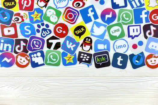 KHARKOV, UKRAINE - MAY 5, 2022 Paper logos of most popular social networks and mobile messengers on wooden background. Facebook instagram youtube twitter tiktok twitch reddit etc. photo