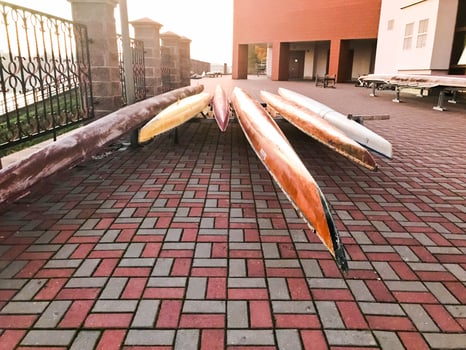 Large team long multi-seater paddle boats for water sports on the beach on stone tiles photo