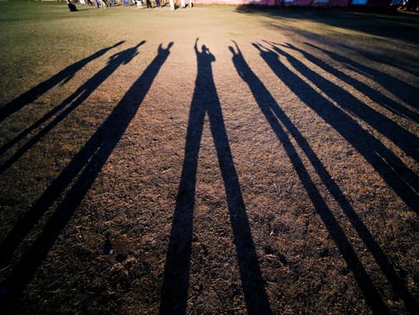 Friends creating a long shadows in the evening on a school field photo