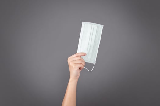 Hand holding a face mask isolated on background. photo