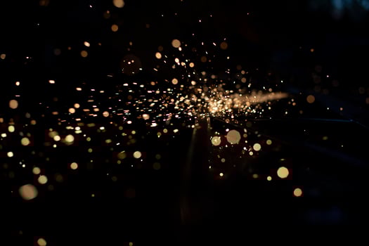 Sparks in dark. Stream of lights on black background. Metal crushing. High temperature. photo