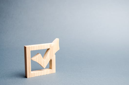wooden checkmark for voting on elections on a gray background. Presidency or parliamentary elections, a referendum. Survey of the population, statistics, task. Democracy and freedom. Selective focus photo