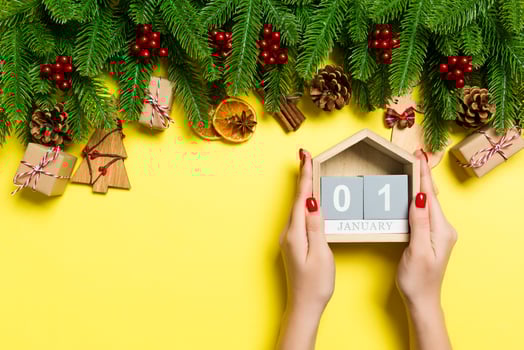 Top view of female hands holding calendar on yellow background. The first of January. Holiday decorations. New Year concept photo