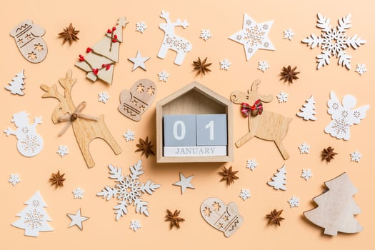 Festive decorations and toys on orange background. Top view of wooden calendar. The first of January. Happy New Year concept photo