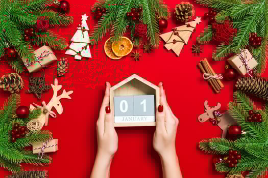Top view of female hands holding calendar on red background. The first of January. Holiday decorations. New Year concept photo