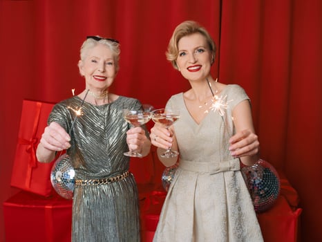 Two beautiful stylish mature senior women in dresses with sparklers and glasses celebrating new year. Christmas, family, friends, new year, Fun, party, style, celebration concept photo
