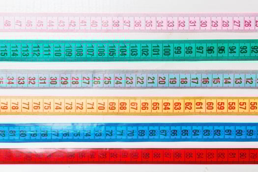 Close up of a group of colorful measure tapes lying in rows as a background. Diet concept on wooden background photo