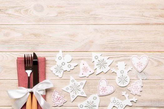 Top view of fork and knife on napkin on wooden background. Different christmas decorations and toys. New Year dinner concept with empty space for your design photo
