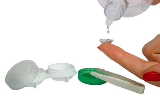 Girl's hand holding the lens on your finger and washed with liquid, box and tweezers for the lens photo