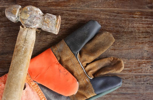 old Hammer and leather gloves on wood background photo
