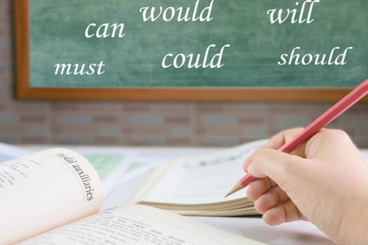 hand holding pencil over blurred textbook on table photo