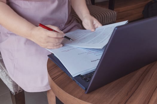 woman's hand holding red pen checking on essay spelling photo