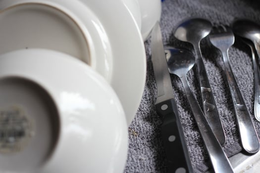 Spoons, fixings, knives and dishes are placed around the sink after washing. photo