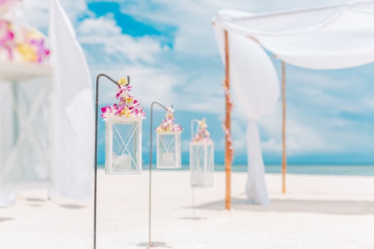 Dream romantic beach wedding decoration, white sand and blue cloudy sky. Couple love honeymoon and anniversary celebration, sunny soft pastel colored setting, flowers and candles under white curtains photo