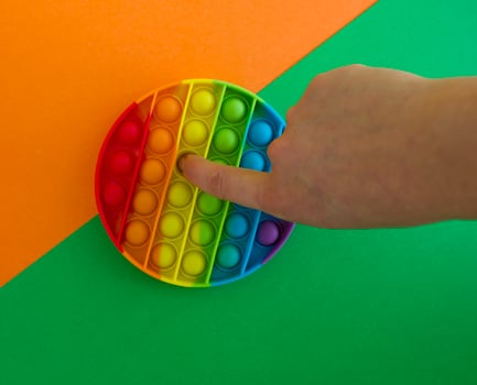 Pop it toy on a green and orange background, a person's hand photo