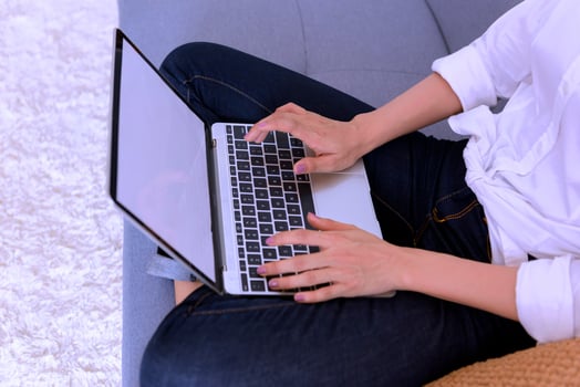 Happy casual beautiful woman working on a laptop sitting on the bed in the house. photo