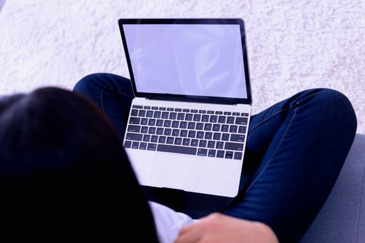 Happy casual beautiful woman working on a laptop sitting on the bed in the house. photo