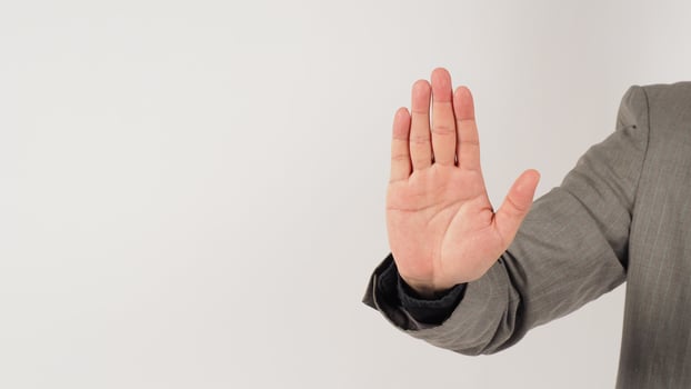 The hand is doing no or stop a hand sign in a grey suit on white background. photo