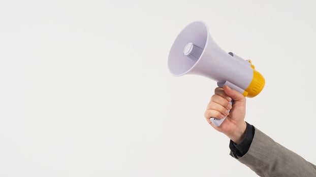 The man's hand is holding a megaphone and wears a grey suit on white background. photo