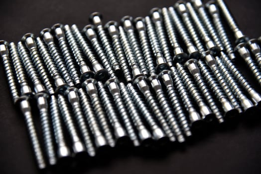 Shiny steel bolts for fixing furniture. Accessories on a black background. photo