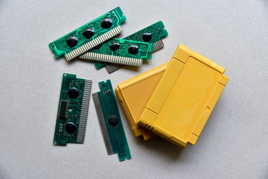 Electronic cartridge board for retro game console. A yellow plastic cartridge on a black background and an electronic board. photo