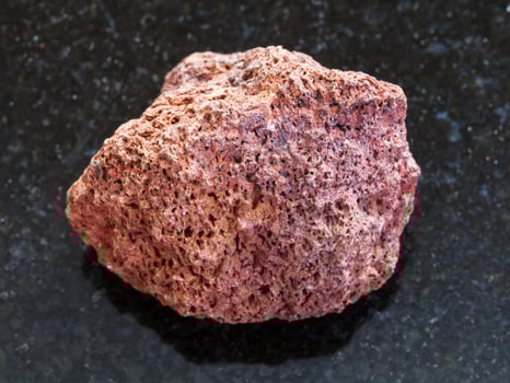 pebble of red pumice stone on dark background photo