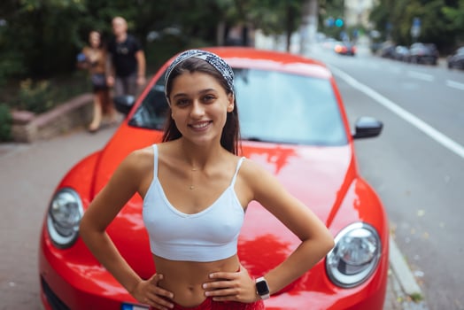 Portrait of pretty Caucasian woman standing against new red car photo