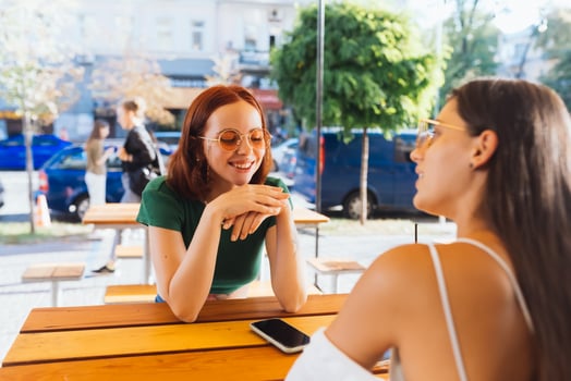 Two pretty girlfriends talking while sitting in a bar outdoors photo