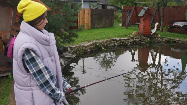 Young beautiful woman is fishing in a small pond photo