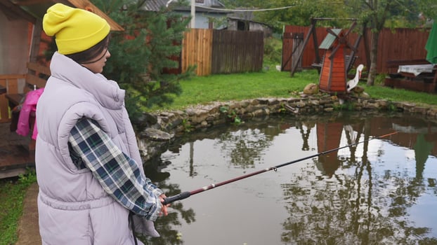 Young beautiful woman is fishing in a small pond photo
