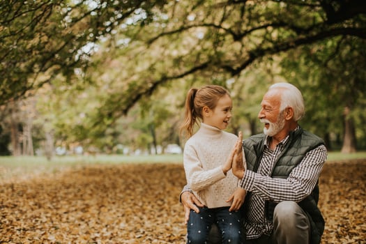 Grandfather spending time with his granddaughter in park on autumn day photo