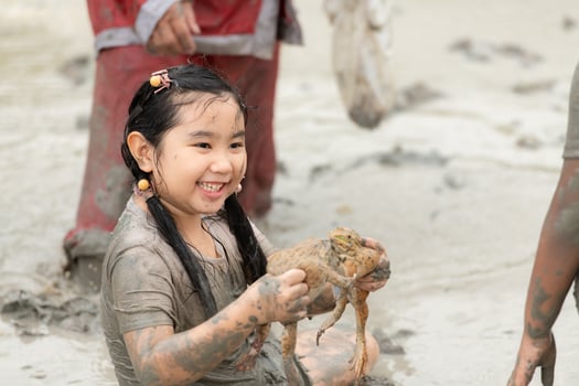 Children have fun playing in the mud in the community fields and catching a frog in a muddy field. photo
