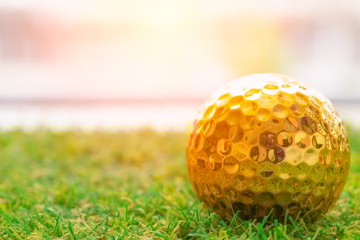 Golden golf ball on green grass with white space for text photo