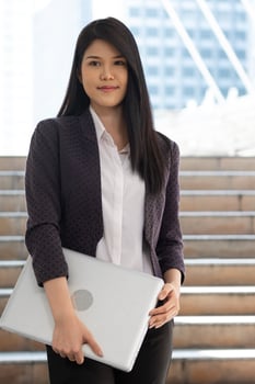 Young Asian woman sthanding and holding labtop computer  in the university, people education concept. photo