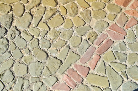 The texture of the stone road, pavement, walls of large gray old medieval round strong stones, cobblestones. The background photo